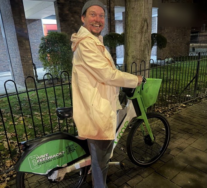 Simon Whale grinning beside a green hire bike